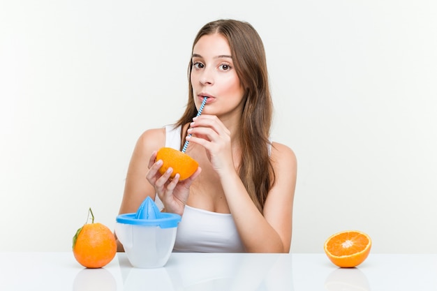 Jeune femme caucasienne, boire une orange avec une paille.