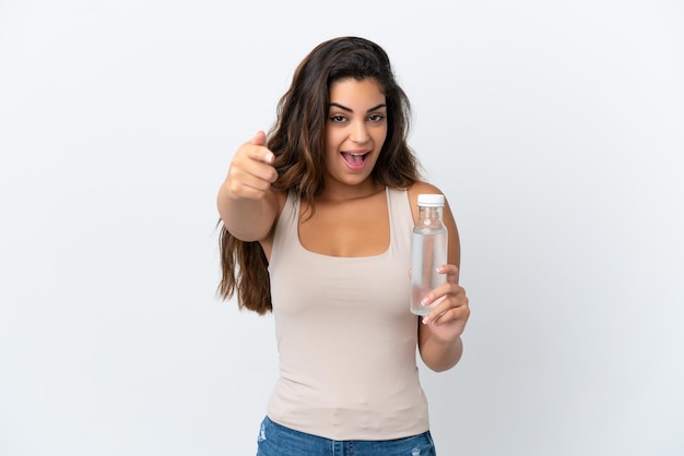 Jeune femme caucasienne avec une bouteille d'eau isolée sur fond blanc surpris et pointant vers l'avant