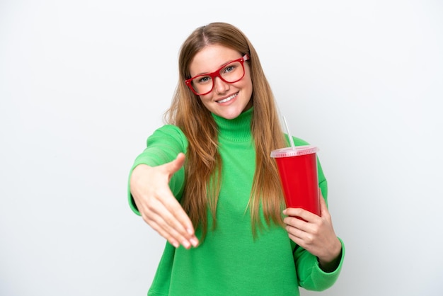 Jeune femme caucasienne buvant du soda isolé sur fond blanc se serrant la main pour conclure une bonne affaire