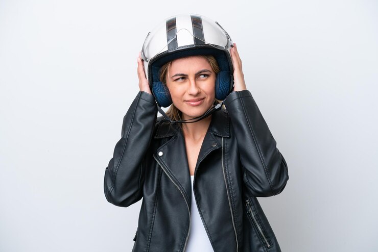 Photo jeune femme caucasienne avec un casque de moto isolé sur fond blanc frustré et couvrant les oreilles