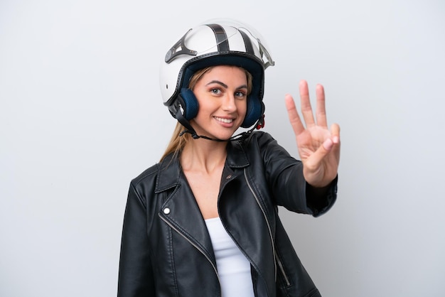 Jeune femme caucasienne avec un casque de moto isolé sur fond blanc heureux et comptant trois avec les doigts