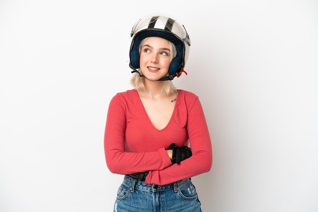 Jeune femme caucasienne avec un casque de moto isolé sur fond blanc en pensant à une idée tout en levant les yeux