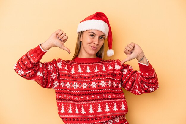 Une jeune femme caucasienne célébrant Noël isolée sur fond jaune se sent fière et confiante, exemple à suivre.