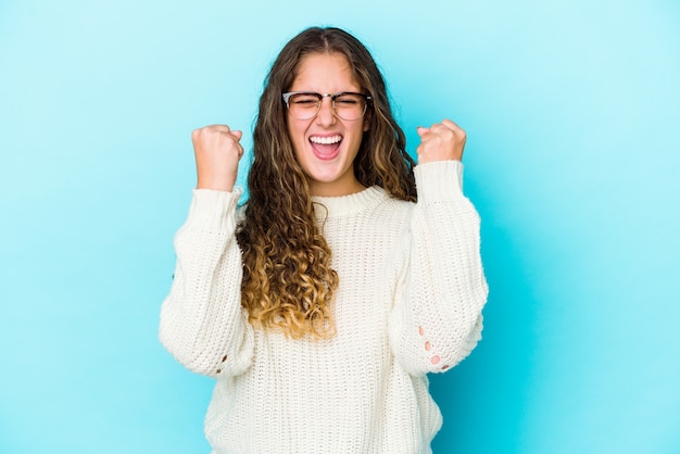 Jeune femme caucasienne cheveux bouclés isolé acclamant insouciant et excité. Concept de victoire.