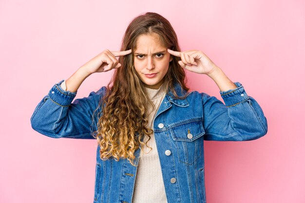 Jeune femme caucasienne concentrée sur une tâche, gardant l'index pointant la tête.