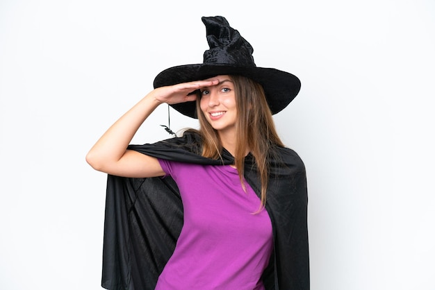 Jeune femme caucasienne en costume de sorcière isolée sur fond blanc regardant loin avec la main pour regarder quelque chose