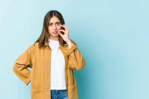 Jeune femme caucasienne avec les doigts sur les lèvres en gardant un secret.