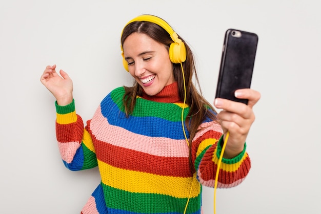 Jeune femme caucasienne écoutant de la musique avec des écouteurs touchant son téléphone portable