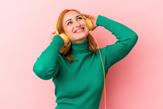 Jeune femme caucasienne écoutant de la musique isolée sur fond rose