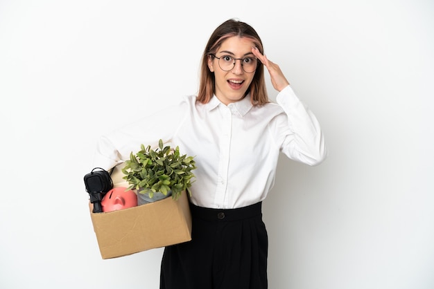 Jeune femme caucasienne emménageant dans une nouvelle maison parmi des boîtes isolées sur fond blanc avec une expression faciale surprise et choquée