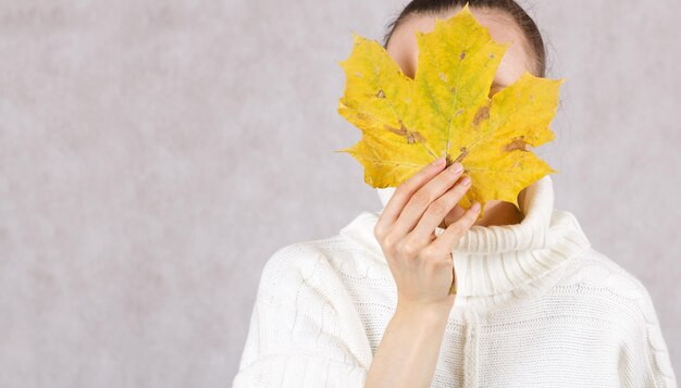 Jeune femme caucasienne entre 30 et 40 ans vêtue d'un chandail tricoté avec feuille d'érable jaune. Fermer