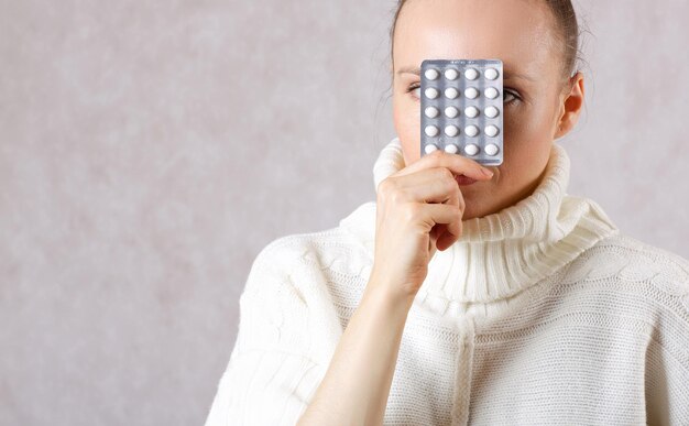 Jeune femme caucasienne entre 30 et 40 ans vêtue d'un pull tricoté avec des médicaments. Fermer