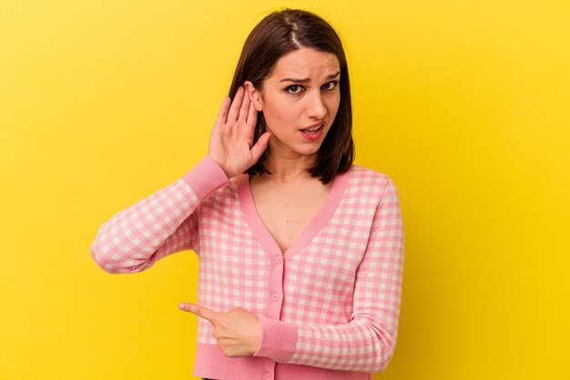 Jeune femme caucasienne essayant d'écouter un potin.