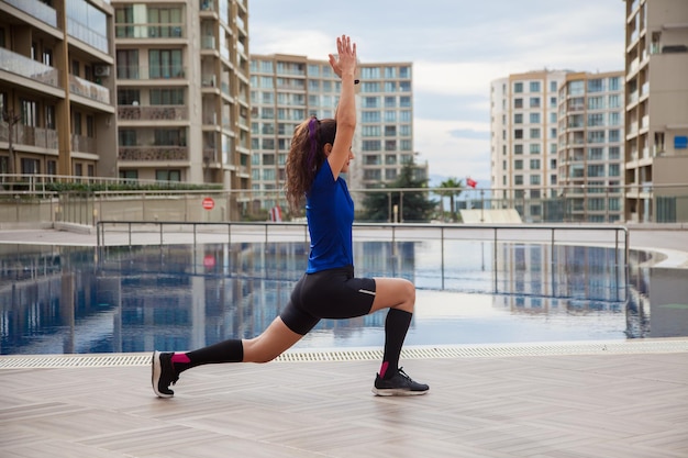 Jeune femme caucasienne faisant des exercices à l'extérieur à côté de la piscine Sport en temps de pandémie