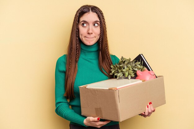 Jeune femme caucasienne faisant un geste isolé sur fond jaune confus se sent douteux et incertain