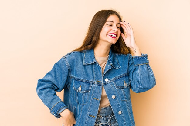 Jeune femme caucasienne isolée en beige joyeux rire beaucoup. Concept de bonheur.