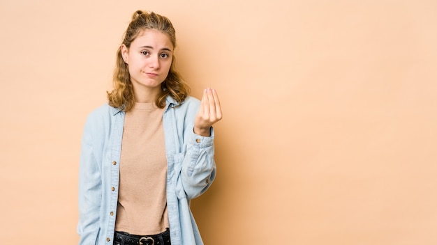 Jeune femme caucasienne isolée sur beige montrant qu'elle n'a pas d'argent.