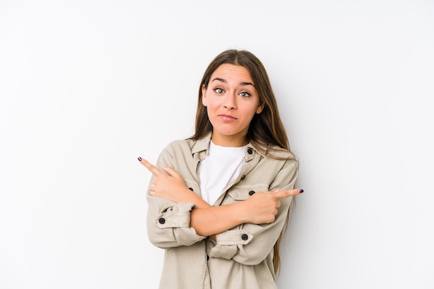 Jeune femme caucasienne isolée sur le côté, essaie de choisir entre deux options.