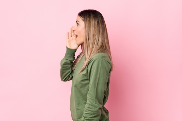 Jeune femme caucasienne isolée criant et tenant la paume près de la bouche ouverte.