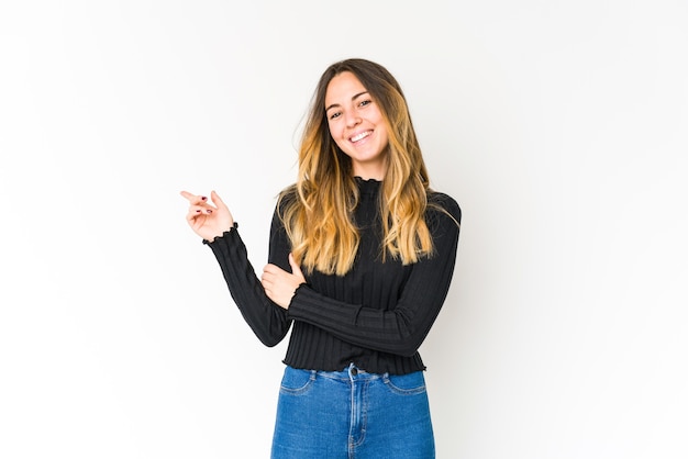 Jeune femme caucasienne isolée sur un espace blanc souriant joyeusement pointant avec l'index loin.