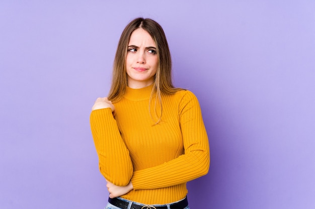 Jeune femme caucasienne isolée sur l'espace violet confuse, se sent douteuse et incertaine.