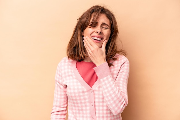 Jeune femme caucasienne isolée sur fond beige ayant une forte douleur aux dents douleur molaire