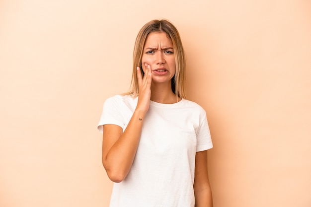 Jeune femme caucasienne isolée sur fond beige ayant une forte douleur dentaire, une douleur molaire.