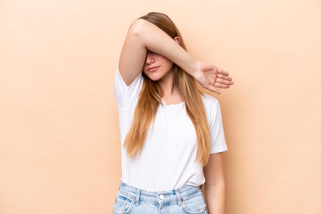 Jeune femme caucasienne isolée sur fond beige couvrant les yeux par les mains