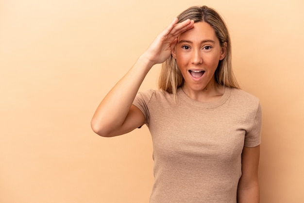 Jeune femme caucasienne isolée sur fond beige crie fort, garde les yeux ouverts et les mains tendues.