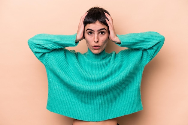 Jeune femme caucasienne isolée sur fond beige étant choquée, elle s'est souvenue d'une réunion importante.