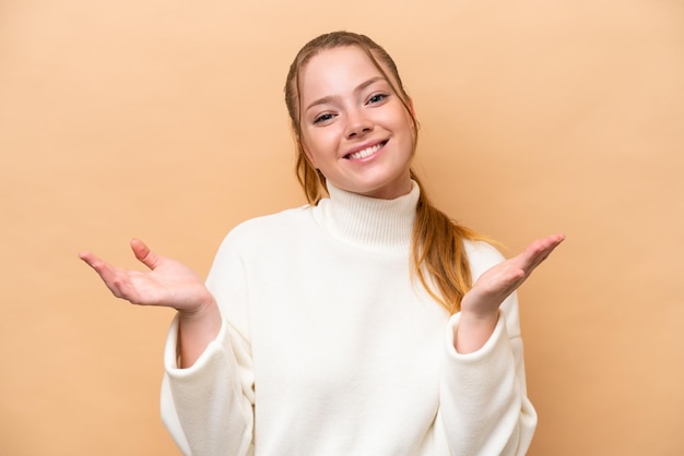 Jeune femme caucasienne isolée sur fond beige heureux et souriant