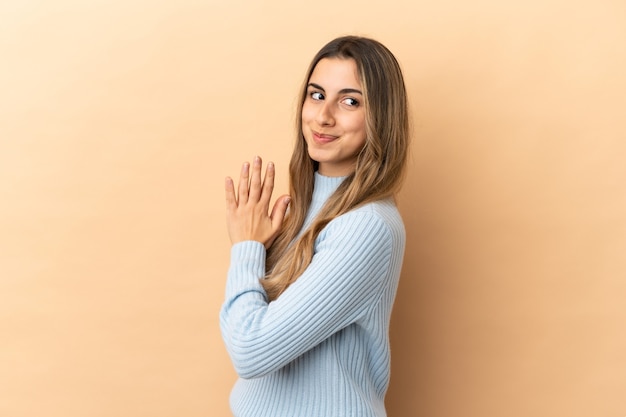 Jeune femme caucasienne isolée sur fond beige intrigant quelque chose