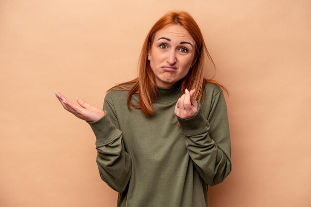 Jeune femme caucasienne isolée sur fond beige montrant qu'elle n'a pas d'argent