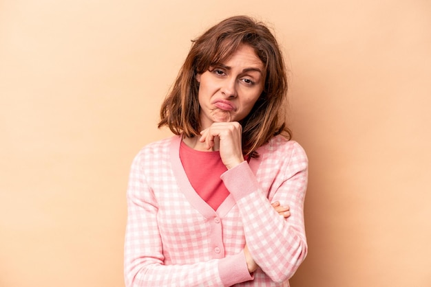 Jeune femme caucasienne isolée sur fond beige pensant et levant les yeux en réfléchissant en contemplant avoir un fantasme