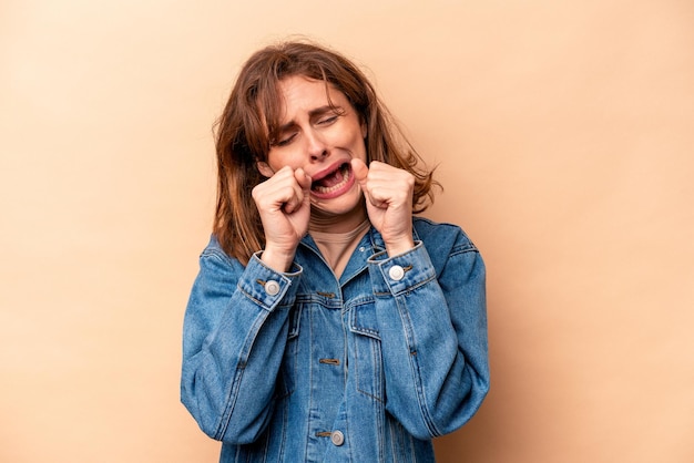 Jeune femme caucasienne isolée sur fond beige pleurnicher et pleurer tristement