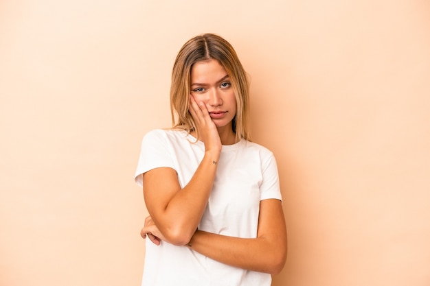 Jeune femme caucasienne isolée sur fond beige qui s'ennuie, est fatiguée et a besoin d'une journée de détente.