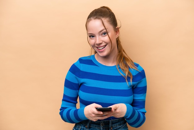 Jeune femme caucasienne isolée sur fond beige surpris et envoyant un message