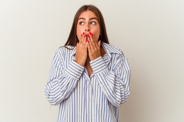 Jeune femme caucasienne isolée sur fond blanc choquée à cause de quelque chose qu'elle a vu.