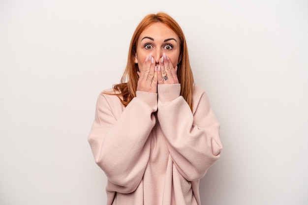 Jeune femme caucasienne isolée sur fond blanc choquée couvrant la bouche avec les mains.