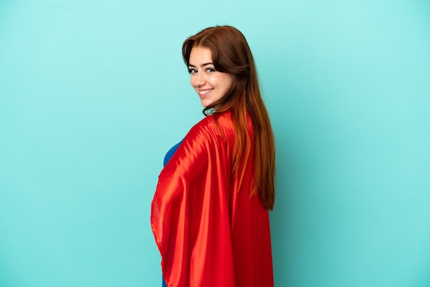 Jeune femme caucasienne isolée sur fond blanc en costume de super-héros et faisant la pose avec les bras à la hanche et souriant