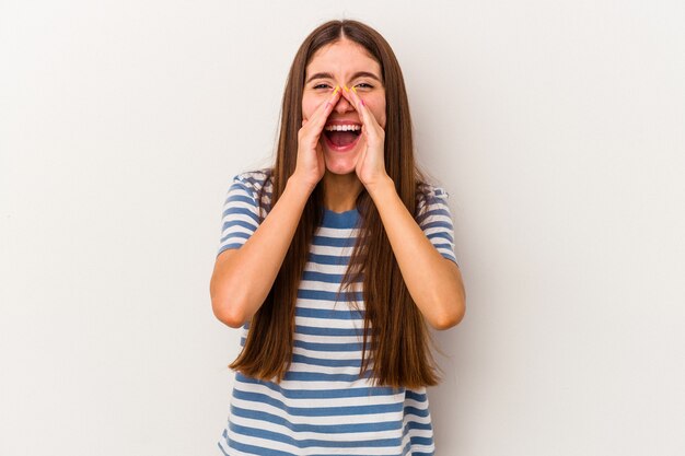 Jeune femme caucasienne isolée sur fond blanc disant un potin, pointant vers le côté rapportant quelque chose.