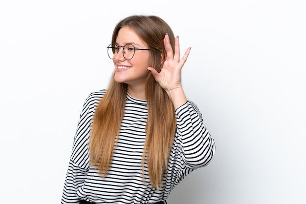 Jeune femme caucasienne isolée sur fond blanc écoutant quelque chose en mettant la main sur l'oreille