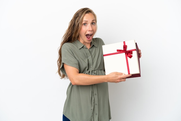 Jeune femme caucasienne isolée sur fond blanc enceinte et tenant un cadeau avec une expression surprise