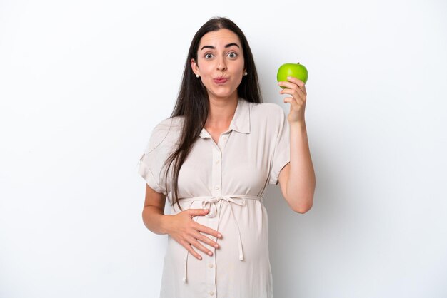 Jeune femme caucasienne isolée sur fond blanc enceinte et tenant une pomme