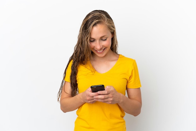 Jeune femme caucasienne isolée sur fond blanc envoyant un message avec le mobile