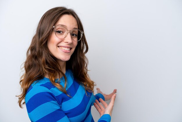 Jeune femme caucasienne isolée sur fond blanc avec des lunettes et présentant quelque chose