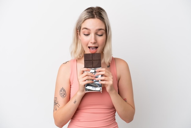 Jeune femme caucasienne isolée sur fond blanc, manger une tablette de chocolat