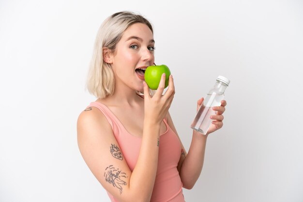 Jeune femme caucasienne isolée sur fond blanc avec une pomme et avec une bouteille d'eau