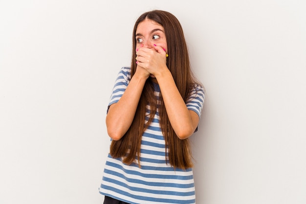 Jeune femme caucasienne isolée sur fond blanc réfléchie à la recherche d'un espace de copie couvrant la bouche avec la main.