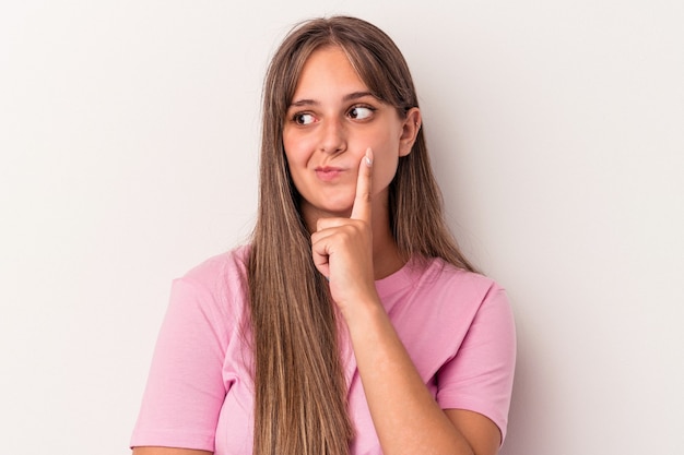 Jeune femme caucasienne isolée sur fond blanc regardant de côté avec une expression douteuse et sceptique.